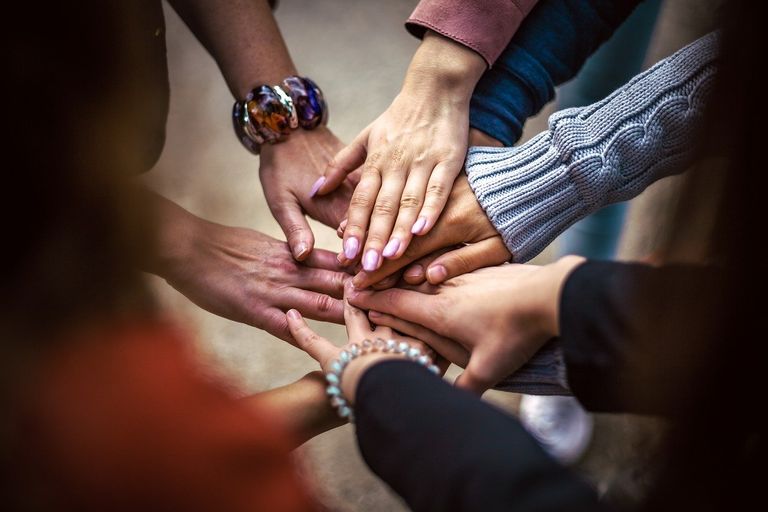 Eine kleine Gruppe von 7 Menschen legen ihre Hände einig übereinander