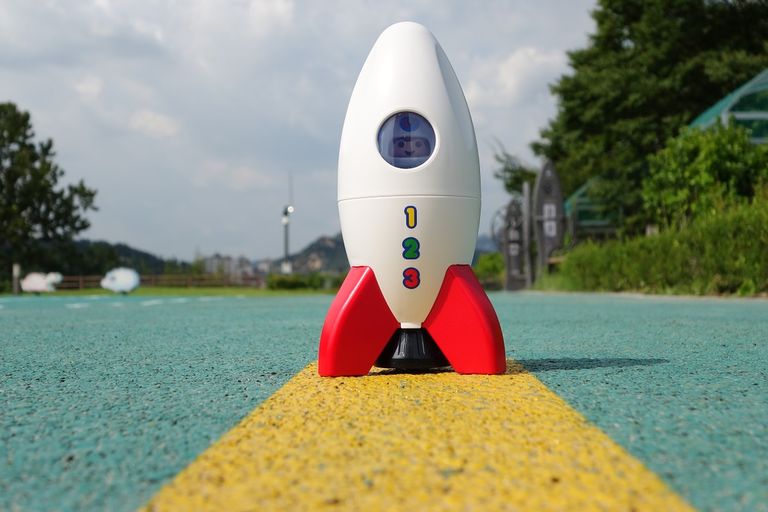 Eine Playmobil-Rakete mit einer Figur darin steht auf einem Sportplatz bereit zum Start